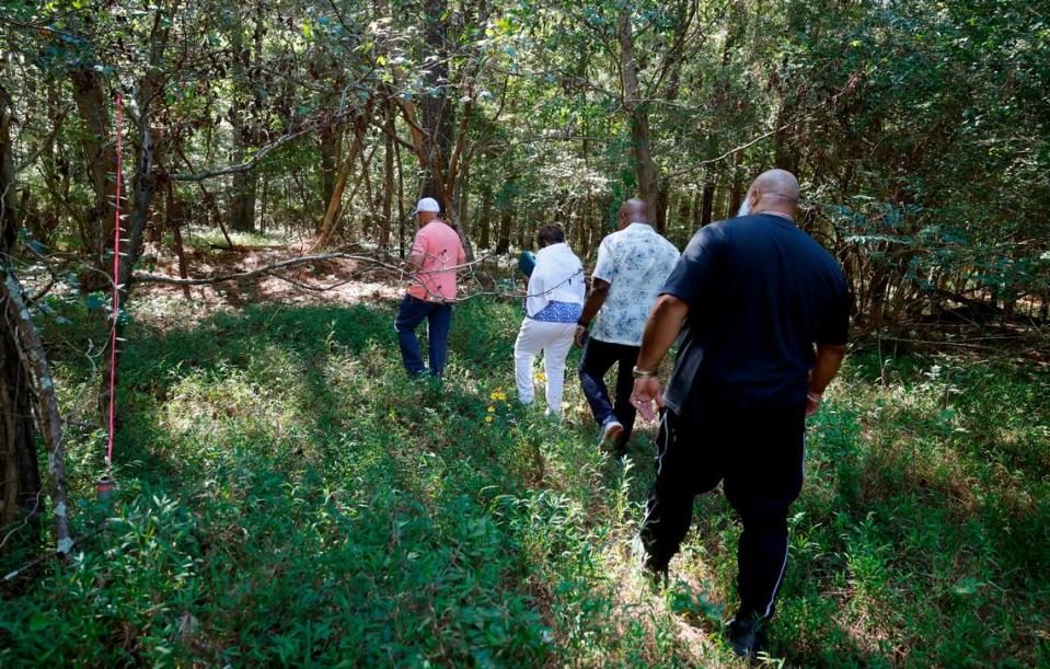 From left Larry Harris, Valerie Frasier, Glenn Evans and Donald Evans, Sr. walk through the woods on Friday, Sept. 15, 2023, to get to Byrd’s Chapel AME Zion Church Cemetery off New Elam Church Rd. in Moncure, N.C.