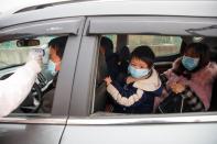 A medical worker in protective suit checks the body temperature of a driver at a checkpoint outside the city of Yueyang