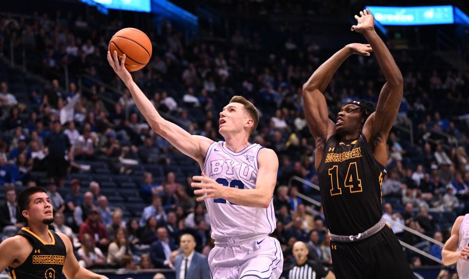 Brigham Young Cougars guard Spencer Johnson (20) lays up the ball ahead of Southeastern Louisiana Lions forward Dylan Canoville (14) as BYU and SE Louisiana play at the Marriott Center in Provo on Wednesday, Nov. 15, 2023. BYU won 105-48. | Scott G Winterton, Deseret News