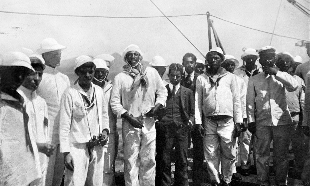 <span>João Cândido Felisberto, centre at left of man in suit, stands among other sailors on the deck of a Brazilian warship in 1910.</span><span>Photograph: Photo 12/Alamy</span>