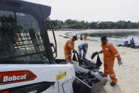 Workers clean oil spill along Sentosa's Tanjong Beach area in Singapore, Sunday, June 16, 2024. An oil spill caused by a dredger boat hitting a stationary cargo tanker has blackened part of Singapore’s southern coastline, including the popular resort island of Sentosa, and sparked concerns it may threaten marine wildlife. (AP Photo/Suhaimi Abdullah)