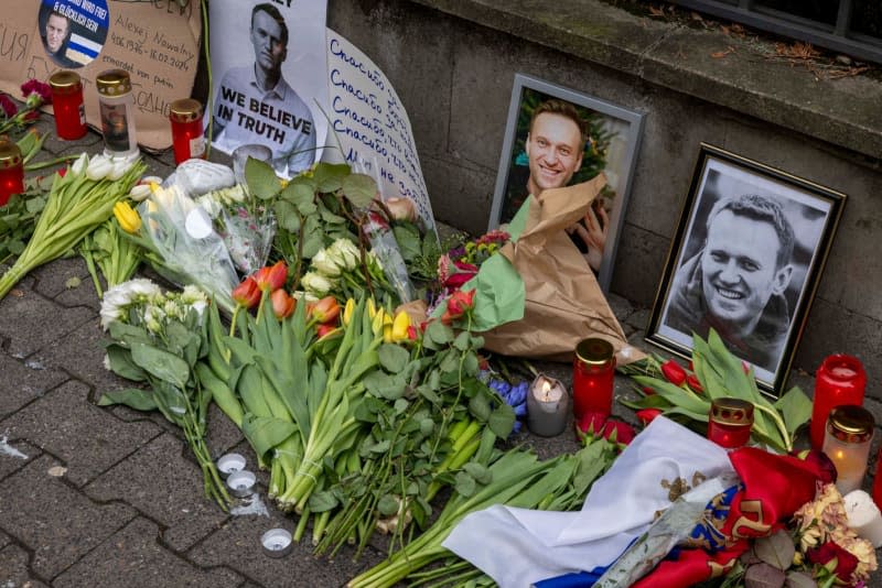 Numerous flowers and candles can be seen alongside photos in memory of the deceased Russian opposition figure Alexey Navalny on the fence of the Russian Consulate General. Helmut Fricke/dpa