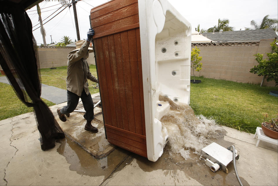 FILE - In this May 6, 2015, file photo, professional spa remover Juan Alexander empties a spa for permanent removal at a residence in which the owner considered it "a waste of water," in Garden Grove, Calif. Gov. Gavin Newsom on Monday, May 10, 2021, declared a drought emergency for most of California, extending a previous order that affected two counties to 41 counties throughout much of the state. (AP Photo/Damian Dovarganes, File)