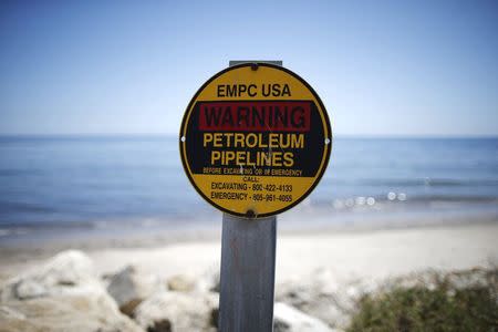 A sign warns of petroleum pipelines next to an oil slick along the coast of Refugio State Beach in Goleta, California, United States, May 20, 2015. REUTERS/Lucy Nicholson