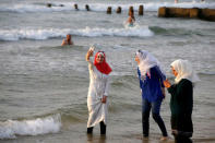 A Muslim woman wearing a Hijab uses her mobile phone to take a photograph as she stands in the Mediterranean Sea at a beach in Tel Aviv, Israel August 30, 2016. REUTERS/Baz Ratner