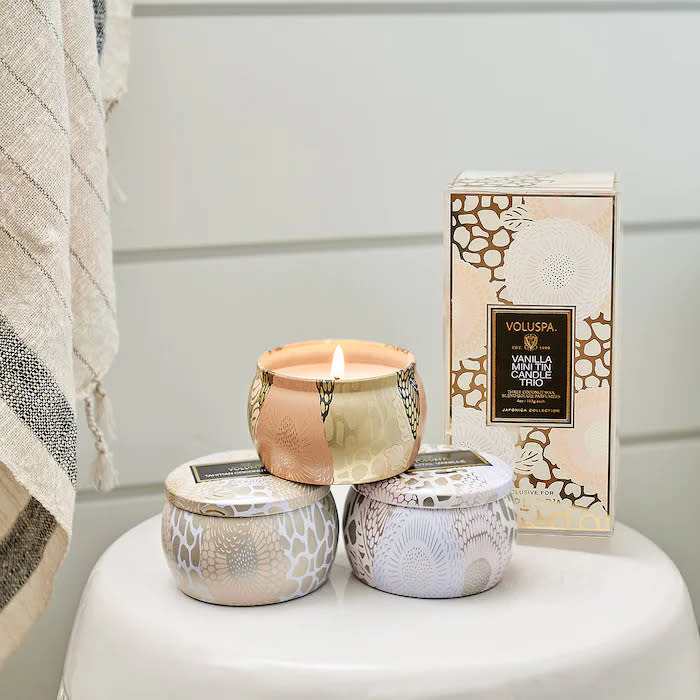 Three mini candle tins places on a white side table