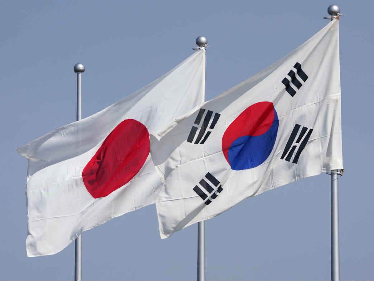 The national flags of Japan (L) and South Korea (R) flutter in the wind on 16 March 2023 (AFP via Getty Images)