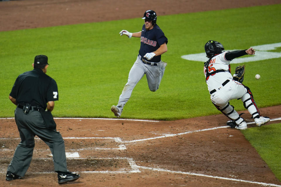 Cleveland Guardians' Myles Straw, center, scores in front of Baltimore Orioles catcher Adley Rutschman (35) as home plate umpire Alfonso Marquez looks on during the seventh inning of a baseball game, Tuesday, May 30, 2023, in Baltimore. The Orioles won 8-5. (AP Photo/Julio Cortez)