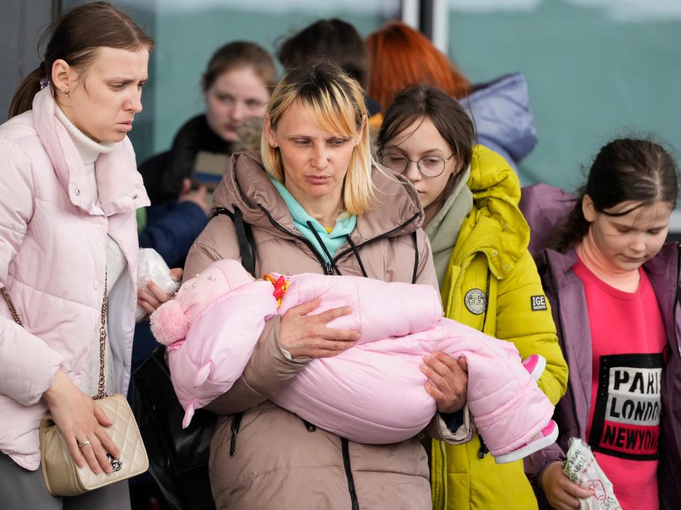 Refugee women with children walk to boarding transport at the central train station in Warsaw, Poland, Thursday, April 7, 2022.