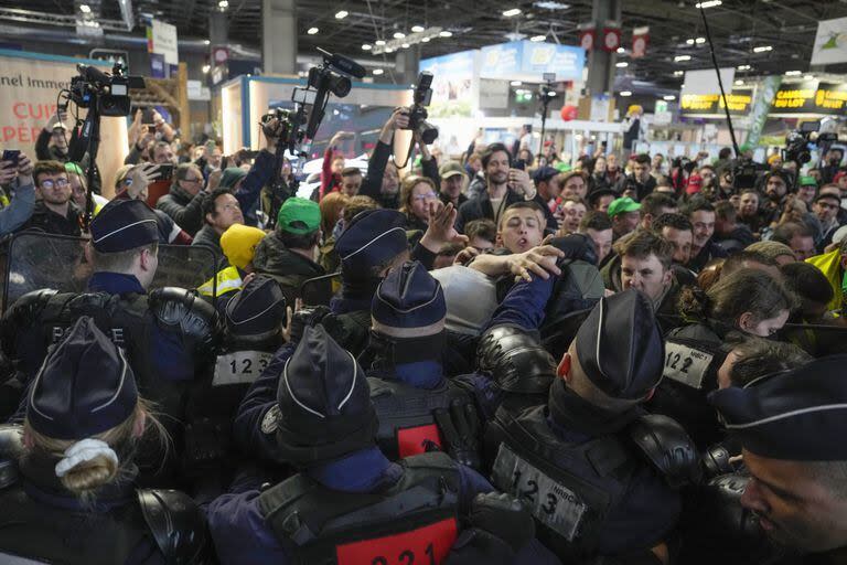 Agricultores enojados se pelean con agentes de policía en la Feria Internacional de Agricultura mientras el presidente francés Emmanuel Macron recorre la exposición el día de su inauguración en París