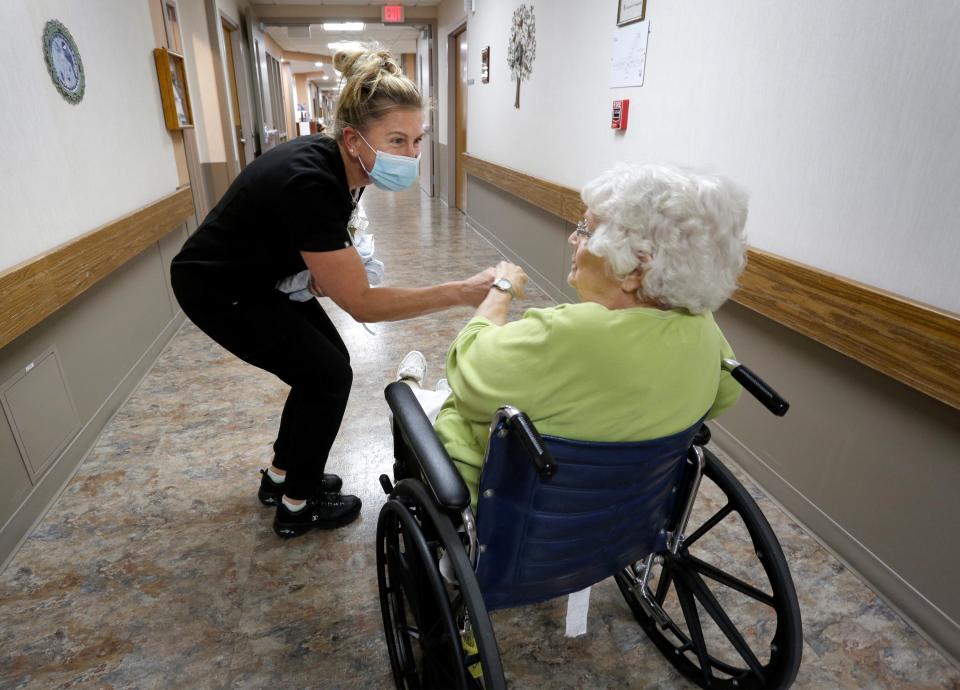 Rocky Knoll CNA Lori Ann Kisiolek bends down to greet resident Mary Bender, Tuesday, October 12, 2021, in Plymouth, Wis.