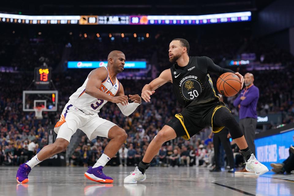 Golden State Warriors guard Stephen Curry (30) dribbles the ball next to Phoenix Suns guard Chris Paul (3) in the second quarter at the Chase Center in San Francisco on March 13, 2023.