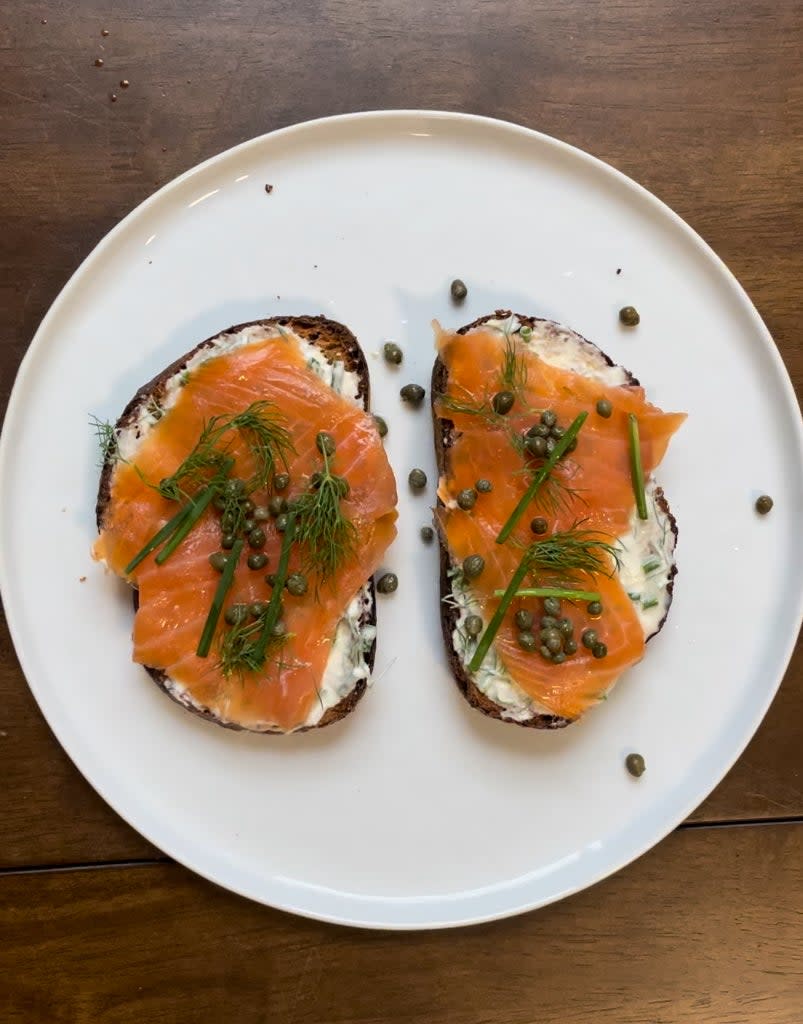 Plate with two slices of toast topped with cream cheese, smoked salmon, and herbs