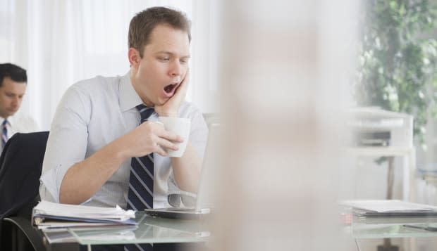 Caucasian businessman drinking coffee and yawning
