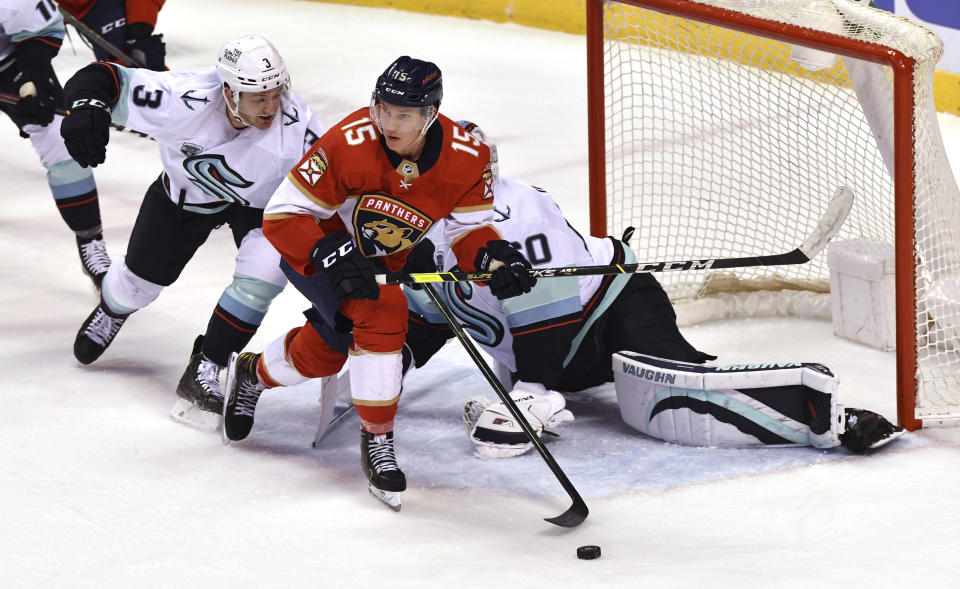 Florida Panthers center Anton Lundell (15) looks to pass as Seattle Kraken defenseman William Borgen (3) closes in and goaltender Chris Driedger (60) looks for the puck during the second period of an NHL hockey game Saturday, Nov. 27, 2021, in Sunrise, Fla. (AP Photo/Jim Rassol)