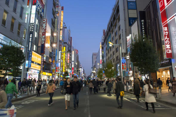 Busy Shinjuku streetscape with neon signs at dusk