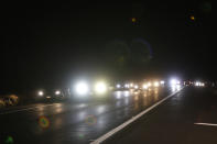 Car travel down Saddle Road near the Mauna Loa eruption, Tuesday, Nov. 29, 2022, near Hilo, Hawaii. Despite local authorities enforcing a no parking zone in the area near the eruption site, many spectators are flooding the area and illegally parking on the side of the highway. (AP Photo/Marco Garcia)