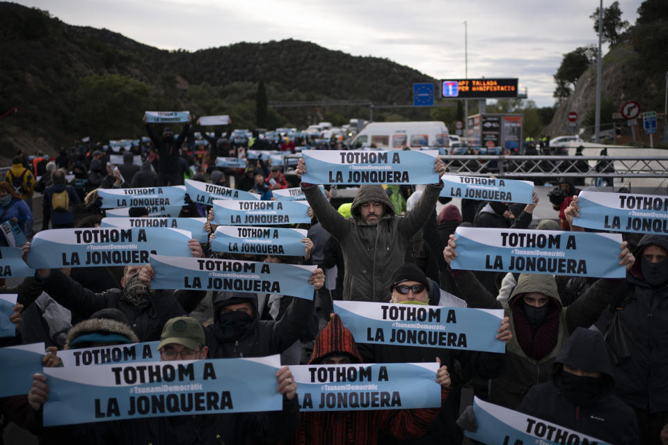 Pro-Catalan independence demonstrators hold banners reading in Catalan "everyone to La Jonquera" as they block a major highway border pass near La Jonquera between Spain and France, Monday, Nov. 11, 2019. Protesters following a call to action by a secretive pro-Catalan independence group have closed off both sides of the AP7 highway at the major transportation hub of La Jonquera between France and Spain. (AP Photo/Felipe Dana)