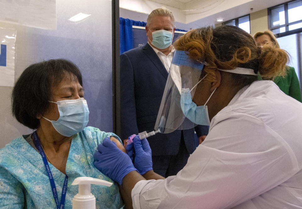 Ontario Premier Doug Ford looks on as the second dose of the Pfizer-BioNTech COVID-19 vaccine in Canada is administered to personal support worker Anita Quidangen by registered nurse Hiwot Arfaso at The Michener Institute in Toronto on Monday, Jan. 4, 2021. (Frank Gunn/The Canadian Press via AP)