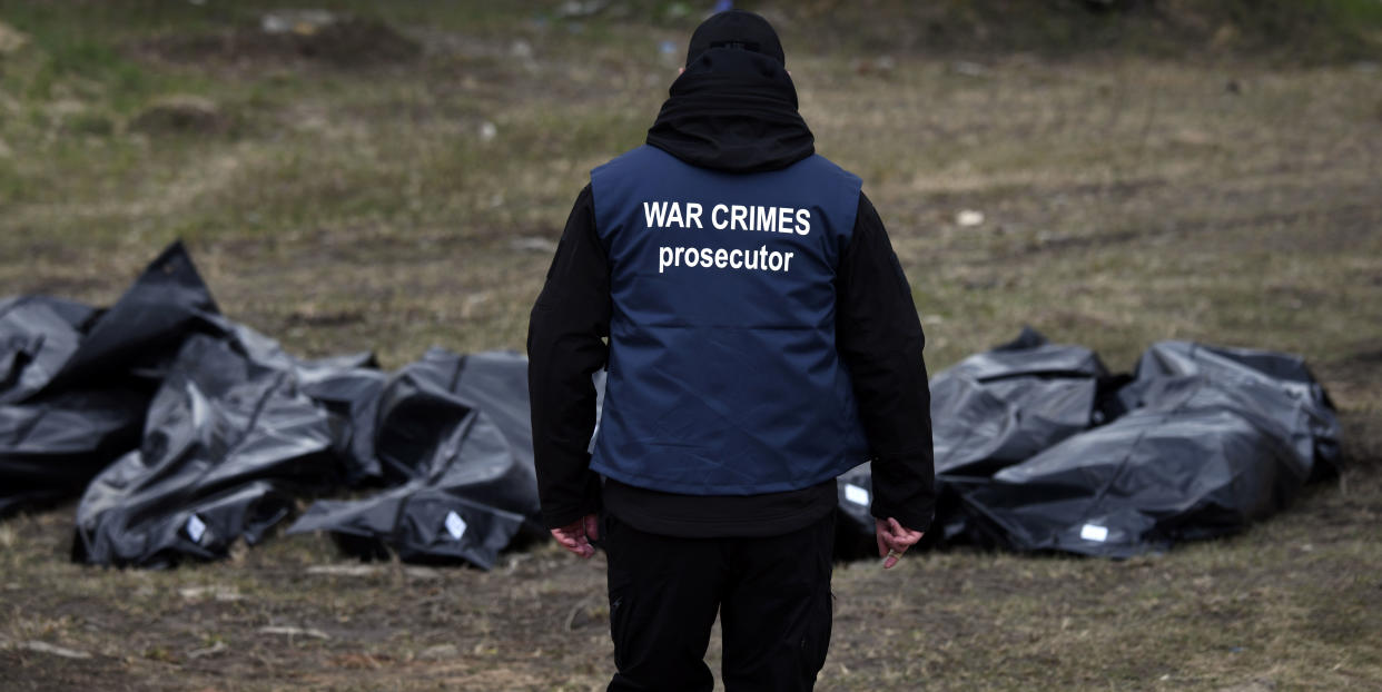 An investigator walks toward bodies that were pulled from a mass grave in Bucha, Ukraine.