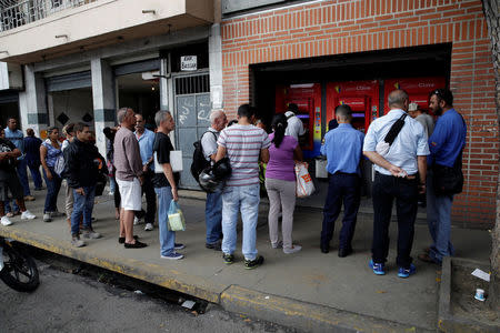 People line up to withdraw cash from an automated teller machine (ATM) outside a Banco de Venezuela branch in Caracas, Venezuela November 25, 2016. REUTERS/Marco Bello