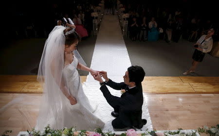 A groom puts a wedding ring on his bride's finger during a wedding ceremony at a budget wedding hall at the National Library of Korea in Seoul, South Korea, May 16, 2015. REUTERS/Kim Hong-Ji