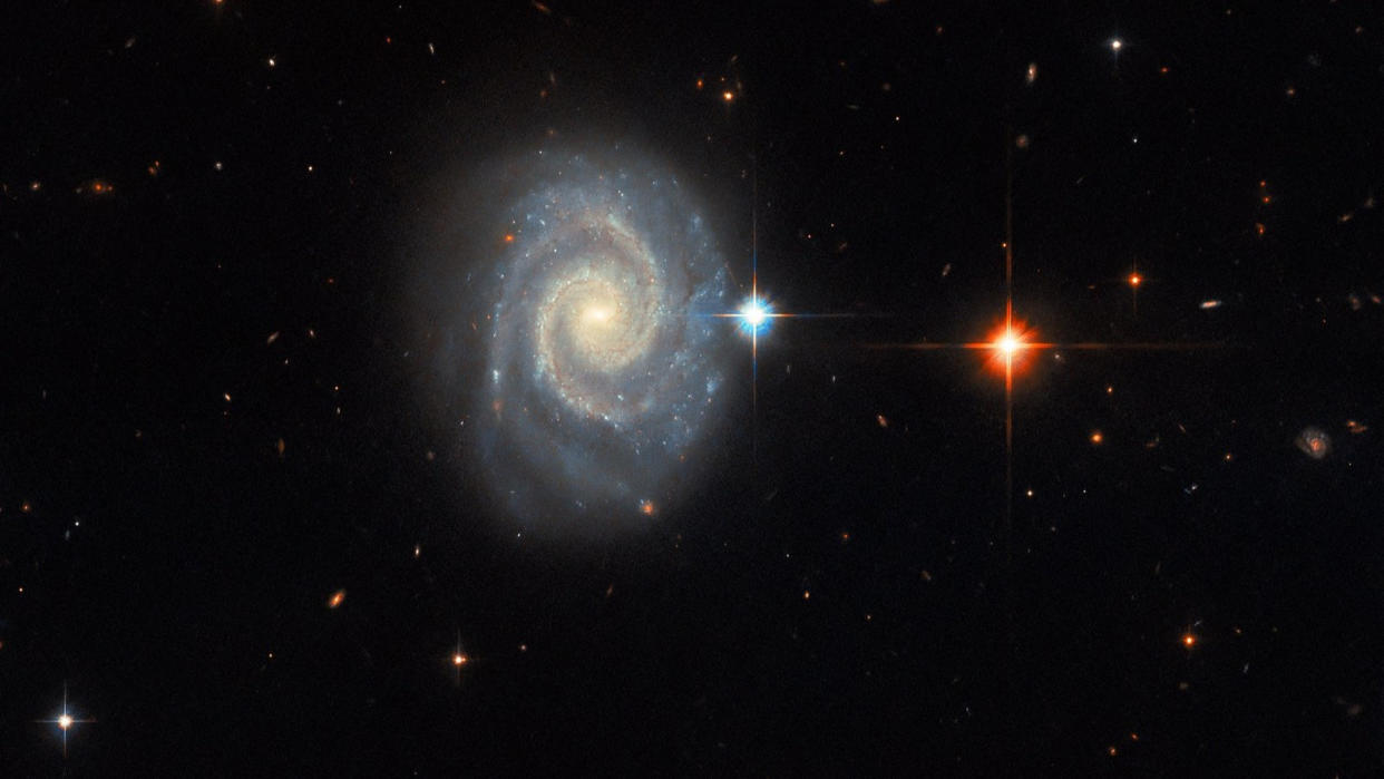  The spiral galaxy MCG-01-24-014 is located 275 million light-years from Earth. Seen face-on, the galaxy has two prominent, well-defined spiral arms and an energetic glowing core known as an active galactic nucleus. . 