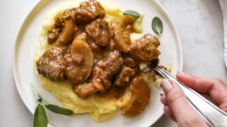 fork eating braised pork and apple casserole