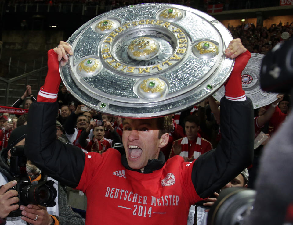 Bayern's Thomas Mueller lifts a mock champions trophy after the German Bundesliga soccer match between Hertha BSC Berlin and Bayern Munich in Berlin, Germany, Tuesday, March 25, 2014. (AP Photo/Michael Sohn)