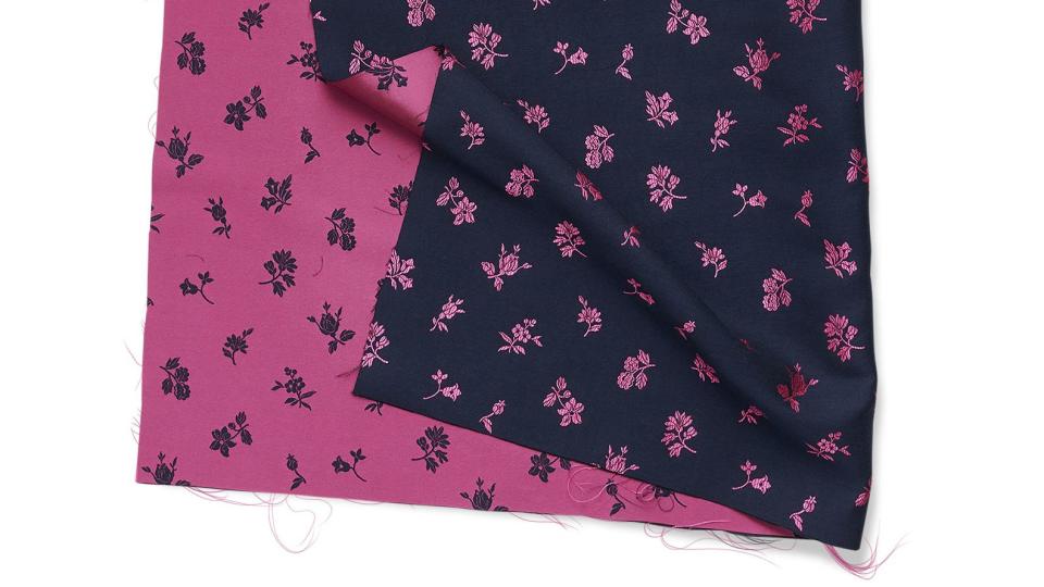 double faced swatch of fabric with one side in a dark magenta color with small print flowers and a darker blue color with reverse magenta flowers on the other side