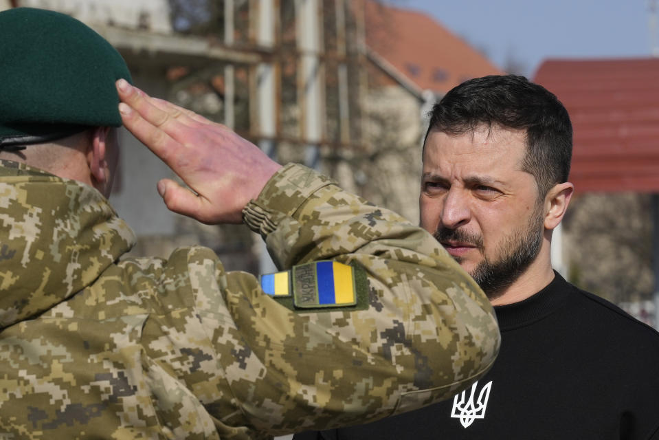 A serviceman salutes Ukrainian President Volodymyr Zelenskyy as he is awarded a medal in Trostianets in the Sumy region of Ukraine, Tuesday March 28, 2023. (AP Photo/Efrem Lukatsky)