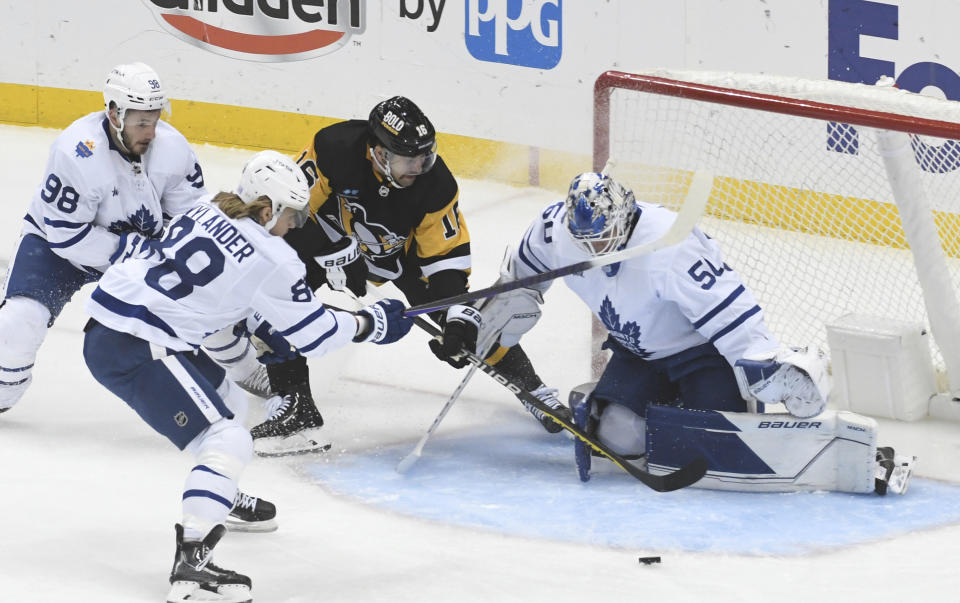 Pittsburgh Penguins left wing Jason Zucker is slowed down by Toronto Maple Leafs defenseman Victor Mete (98) and right wing William Nylander as he shoots on goalie Erik Kallgren during the first period of an NHL hockey game, Saturday, Nov. 26, 2022, in Pittsburgh. (AP Photo/Philip G. Pavely)