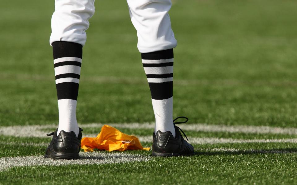 Passiert ein Foul, wirft der Schiedsrichter an der Stelle die Flag auf das Feld. (Bild: iStock / fstockfoto)