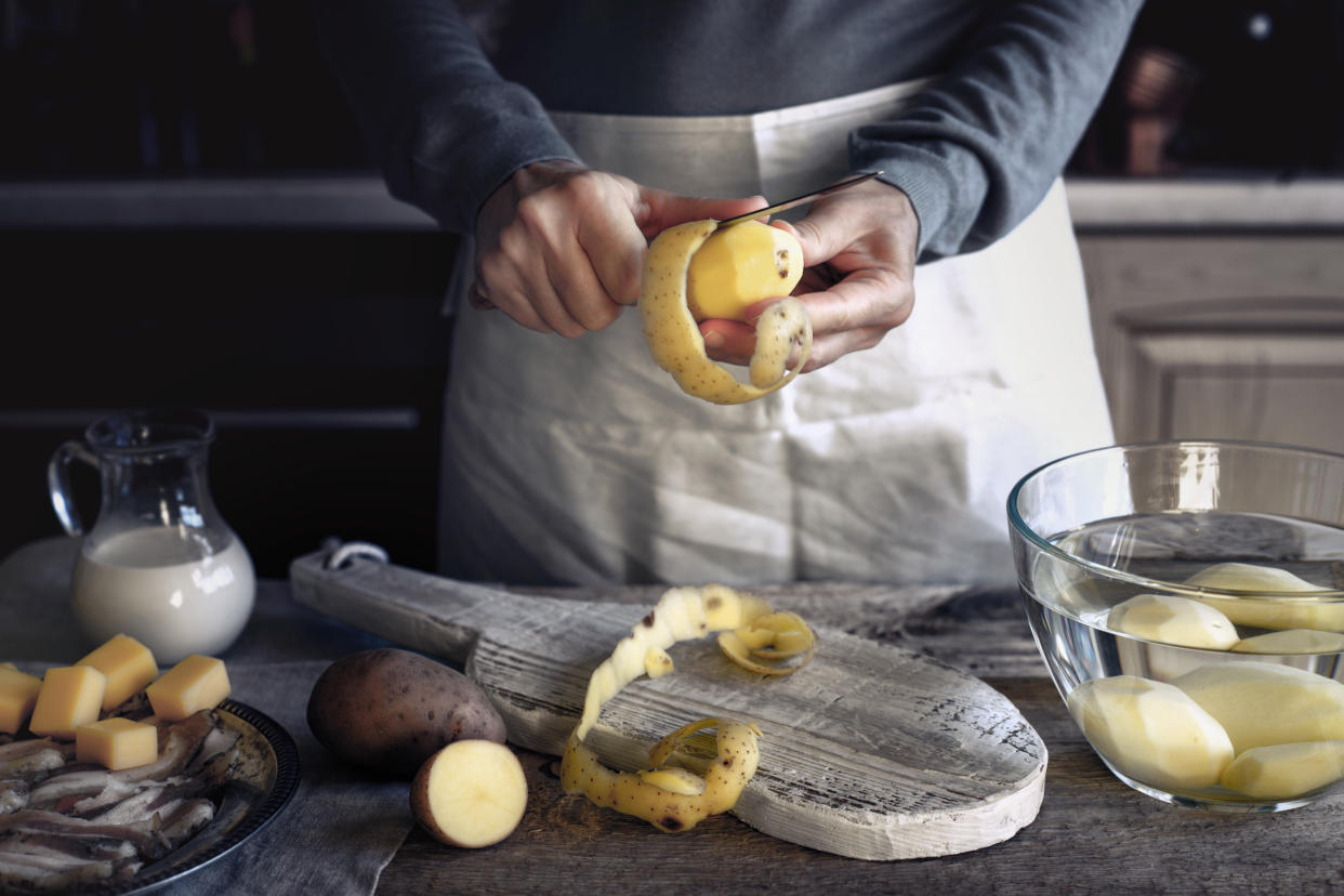 Woman peel potatoes on the wooden table horizontal