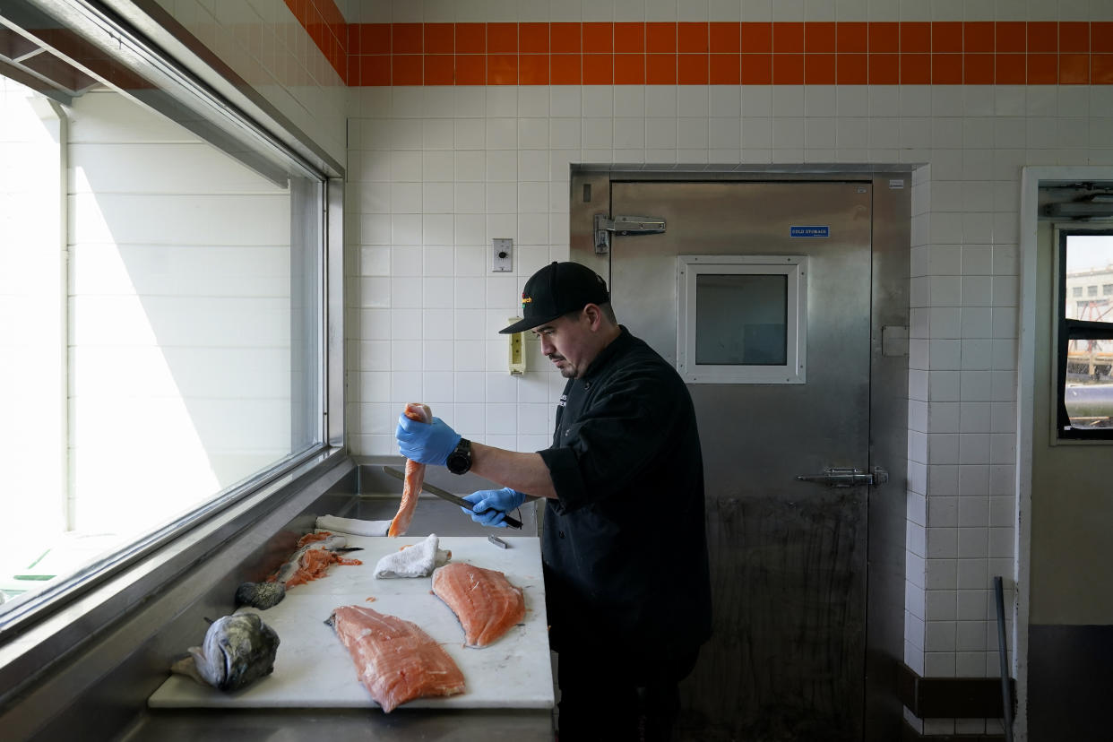 Luis Alvarenga, executive chef at Scoma's, cleans a farm-raised salmon in San Francisco, Monday, March 20, 2023. On April 7, the Pacific Fishery Management Council, the regulatory group that advises federal officials, will take action on what to do about the 2023 season for both commercial and recreational salmon fishing. (AP Photo/Godofredo A. Vásquez)