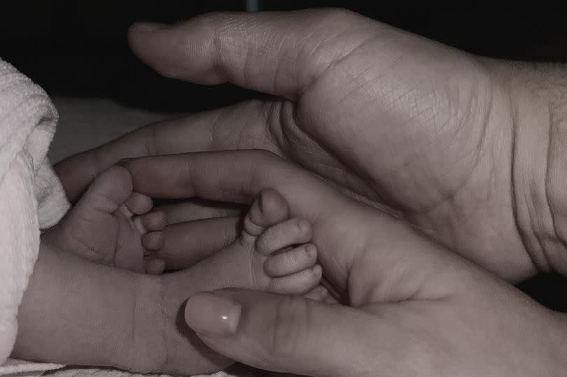 Bethan and Sean cradling their baby girl's feet