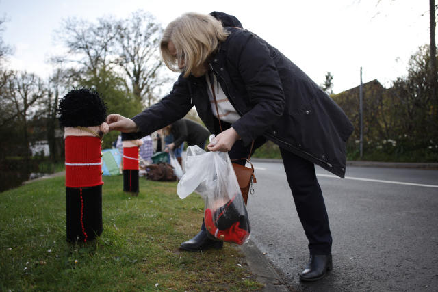 A member of the 'Hurst Hookers' knitting group attaches a knitted figure of a Grenadier Guard to a post in a pre-coronation 'yarn bombing' in the village of Hurst, near Reading, England, Friday, April 21, 2023. Heather Howarth and her friends in the village of Hurst, a stone’s throw from Reading, west of London, have fashioned a woolly coronation procession to rival the pomp and circumstance that will take place when Charles is crowned on May 6 at Westminster Abbey. (AP Photo/David Cliff)