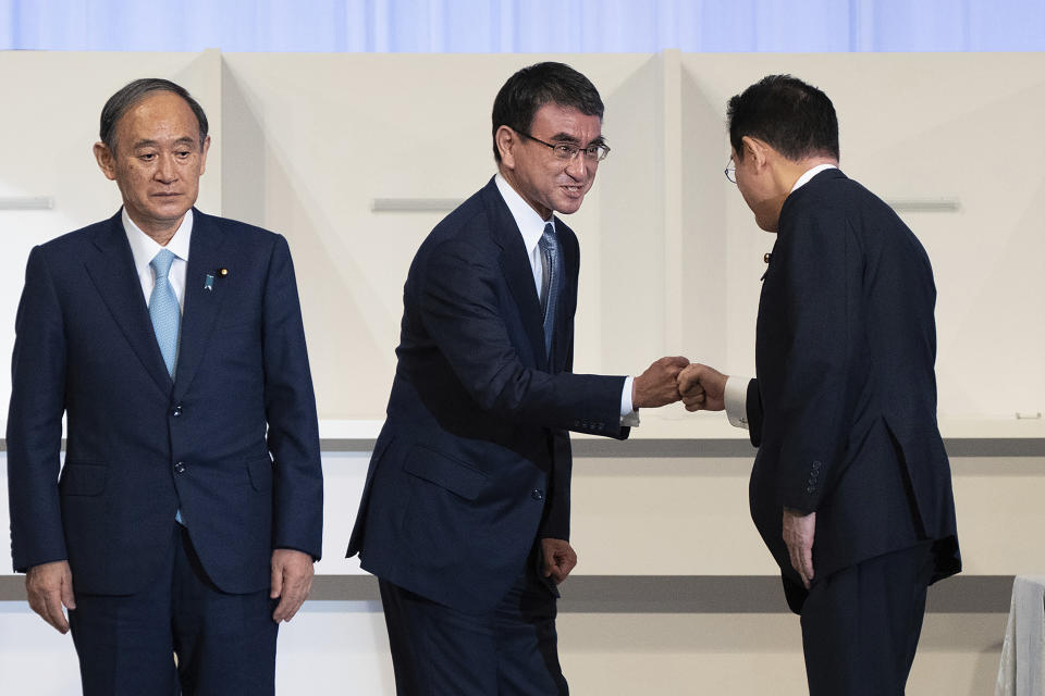 Japan's outgoing Prime Minister Yoshihide Suga, left, pauses while Taro Kono, center, Regulatory Reform and Vaccine minister and a failed leadership candidate, fist bumps with former Foreign Minister Fumio Kishida after Kishida was announced the winner of the Liberal Democrat Party leadership election in Tokyo Wednesday, Sept. 29, 2021. Kishida won the governing party leadership election on Wednesday and is set to become the next prime minister, facing the imminent task of addressing a pandemic-hit economy and ensuring a strong alliance with Washington to counter growing regional security risks. (Carl Court/Pool Photo via AP)