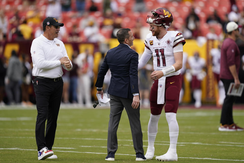 Philadelphia Eagles General Manager Howie Roseman, center, greeting Washington Commanders quarterback Carson Wentz (11) and Washington Commanders head coach Ron Rivera, left, Before the start of an NFL football game, Sunday, Sept. 25, 2022, in Landover, Md. (AP Photo/Alex Brandon)