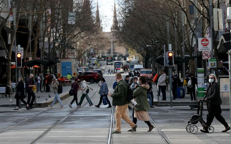 People cross the road in Melbourne, Australia on 28 July 2021, as the city's coronavirus lockdown was lifted - Con Chronis/AFP