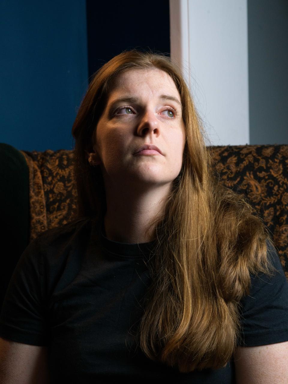 A photograph of a woman sat in a chair looking into the light.