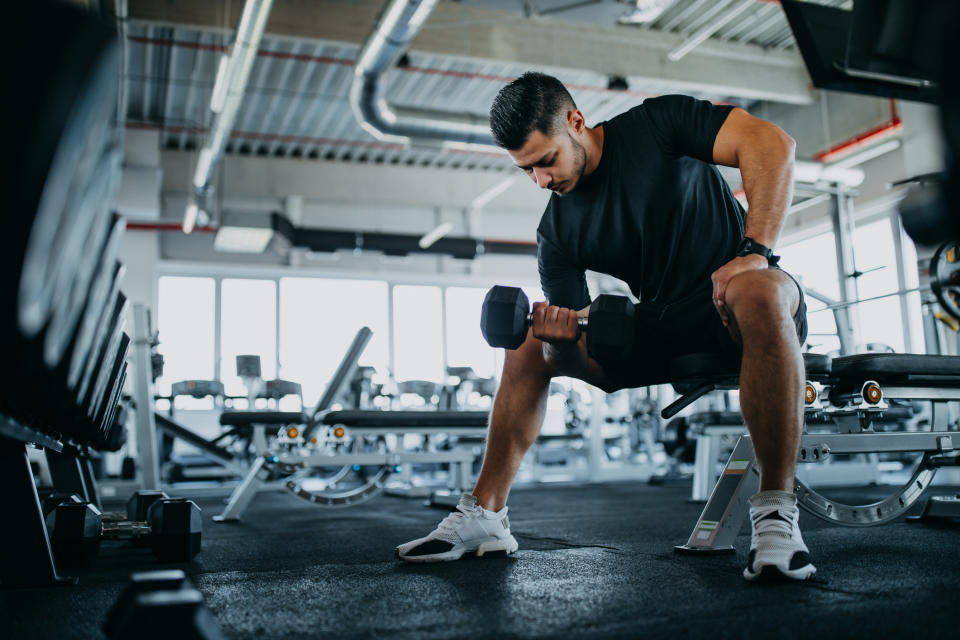 Man performing a dumbbell exercise in a gym setting