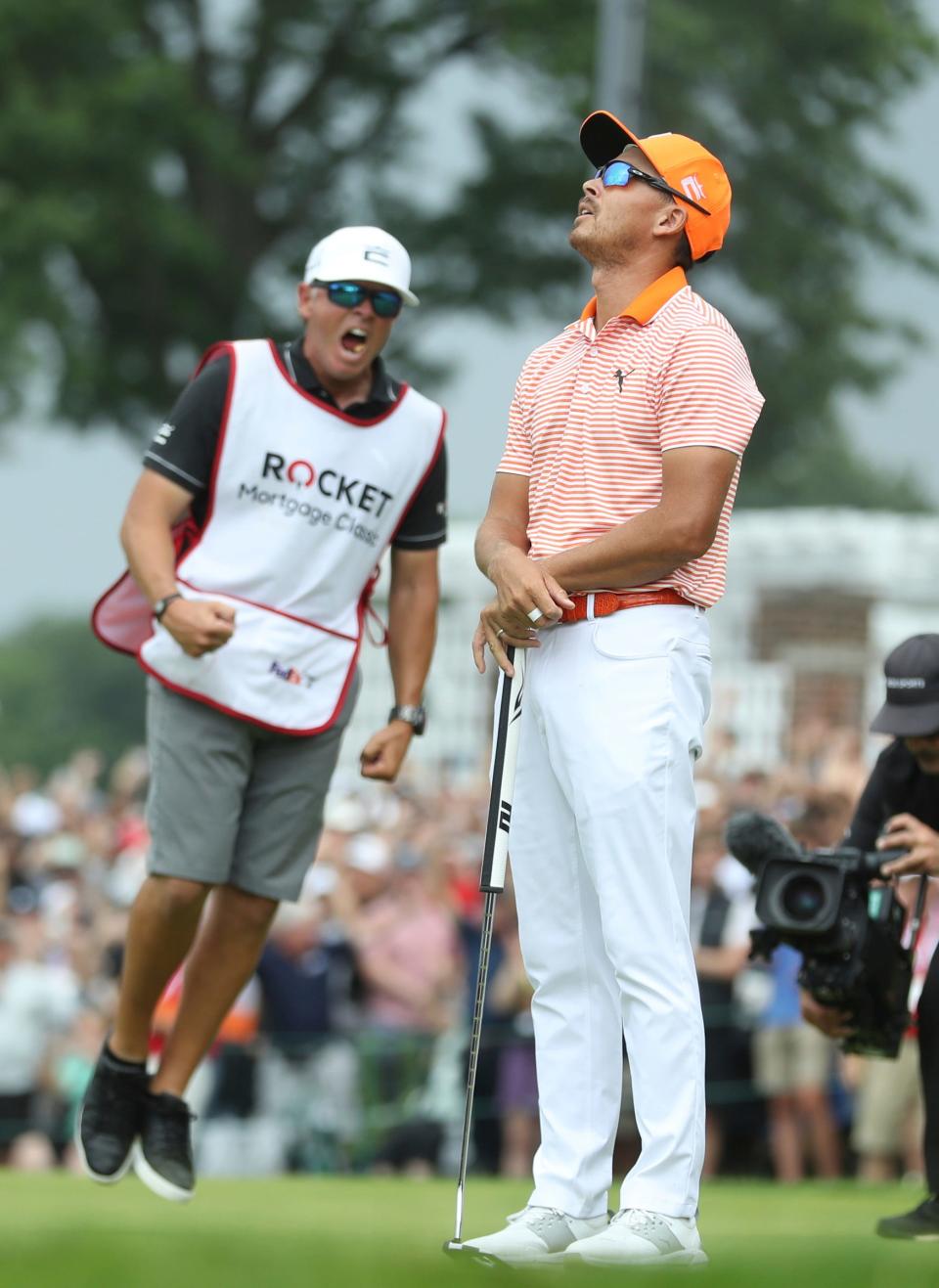 Rickie Fowler, right, and his caddie Ricky Romano react with joy after making birdie on the 18th green to win the Rocket Mortgage Classic in a playoff against Adam Hadwin and Collin Morikawa at Detroit Golf Club on Sunday, July 2, 2023.