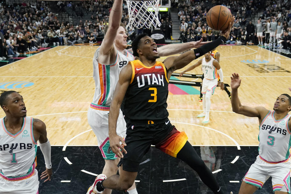 Utah Jazz guard Trent Forrest (3) drives to the basket against San Antonio Spurs center Jakob Poeltl, center, during the second half of an NBA basketball game, Friday, March 11, 2022, in San Antonio. (AP Photo/Eric Gay)