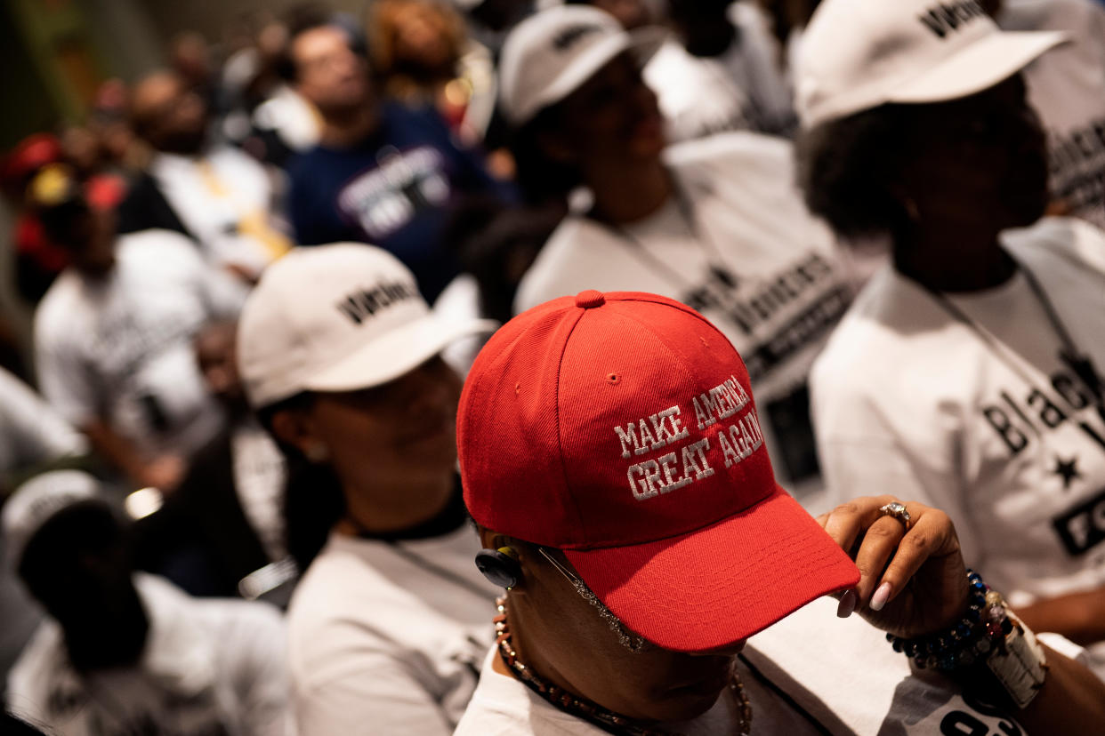 An audience member in a row of African Americans wears a red Make American Great Again cap.