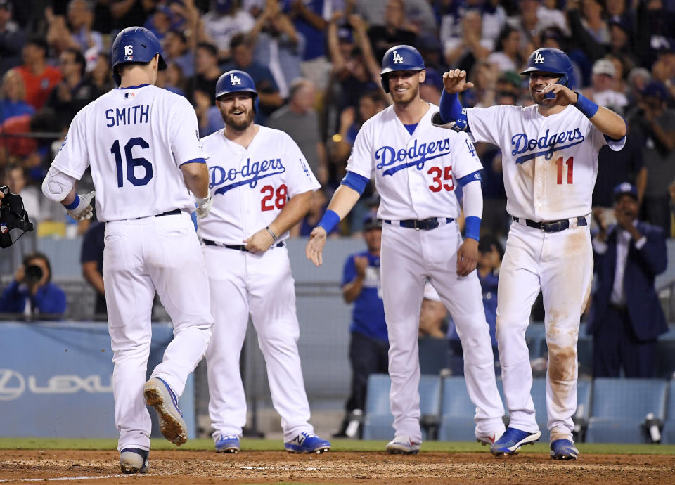 Los Angeles Dodgers' Will Smith, left, scores as teammates Tyler White, Cody Bellinger and A.J. Pollock, from second from left, wait for him after he hit a grand slam during the sixth inning of the team's baseball game against the San Diego Padres on Thursday, Aug. 1, 2019, in Los Angeles. (AP Photo/Mark J. Terrill)