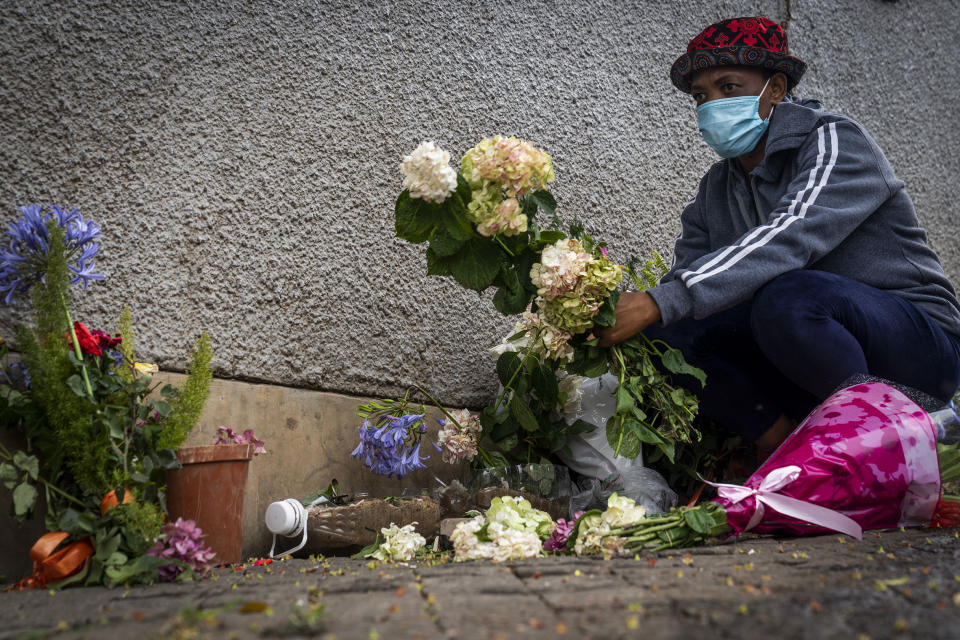 A woman places flowers outside the historical home of Anglican Archbishop Desmond Tutu, in Soweto, Johannesburg, South Africa, Monday, Dec. 27, 2021. At midday in Cape Town bells rang from St. George's Anglican Cathedral to honor Archbishop Emeritus Desmond Tutu, a day after his death. (AP Photo/Shiraaz Mohamed)