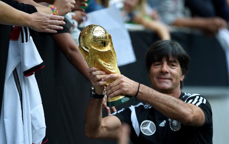 Germany's head coach Joachim Loew shows the World Cup trophy during a public training session of the German national football team in Duesseldorf, Germany on September 1, 2014