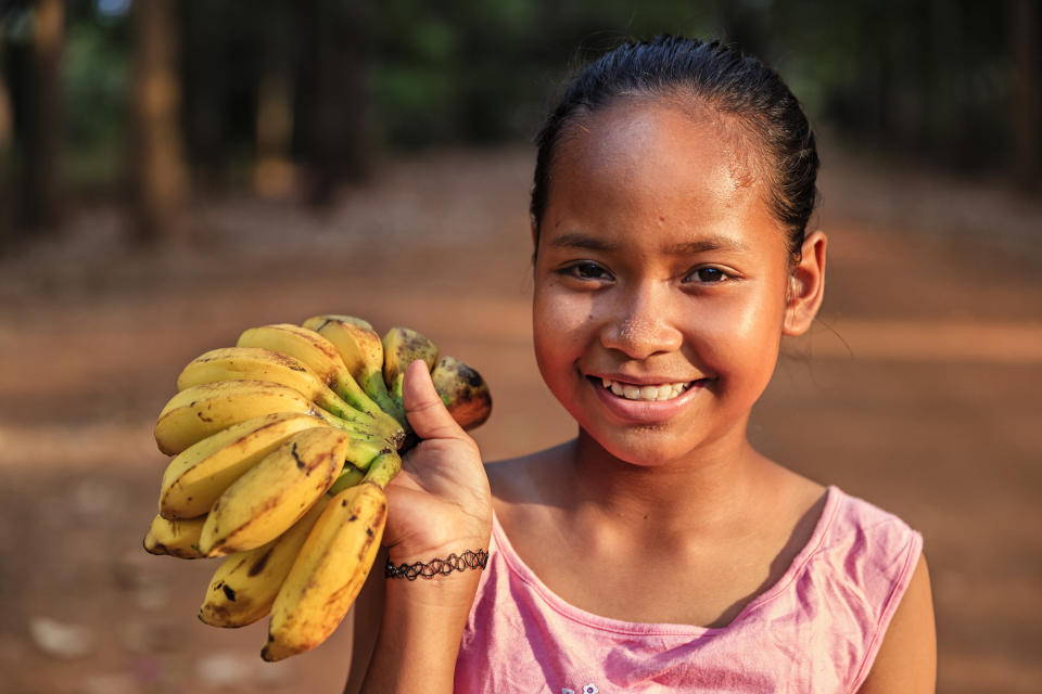 A young Cambodian girl smiles as she sells fresh bananas in a village close to Siem Reap, Cambodia