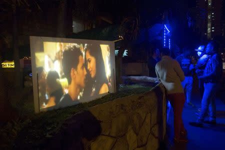 A movie is shown on a screen as clients gather outside a privately-run bar in Havana January 11, 2015. REUTERS/Alexandre Meneghini